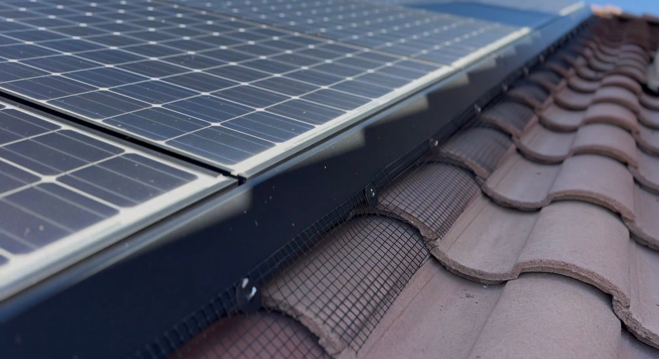 Close-up of black pigeon mesh secured along the edge of solar panels